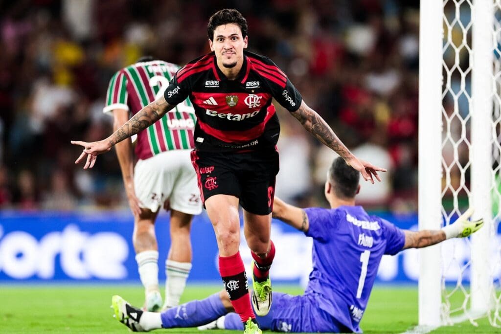 Pedro com braços abertos comemorando gol pelo Flamengo contra o Fluminense; ao fundo, Fábio reclama e Freytes se lamenta