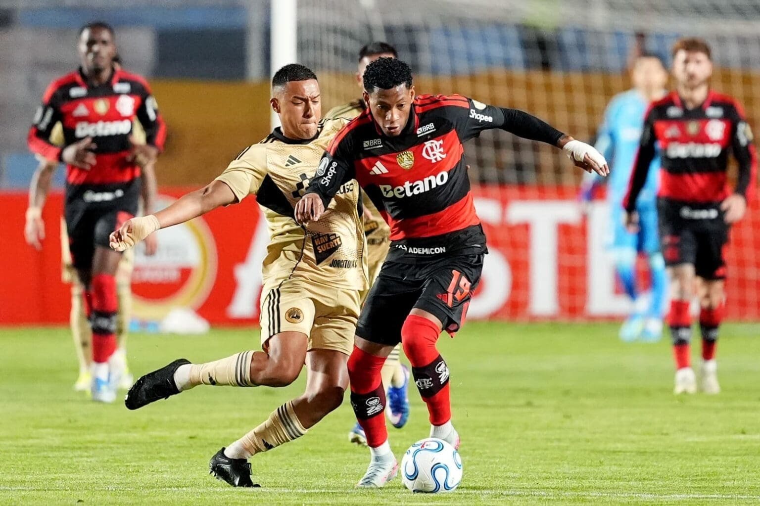 Gonzalo Plata, do Flamengo, carrega a bola, enquanto jogador do Cusco FC tenta o desarme de carrinho
