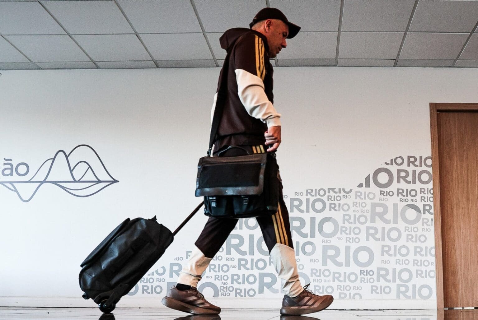 Leonardo Jardim carrega a mala durante embarque da deleção do Flamengo no Galeão