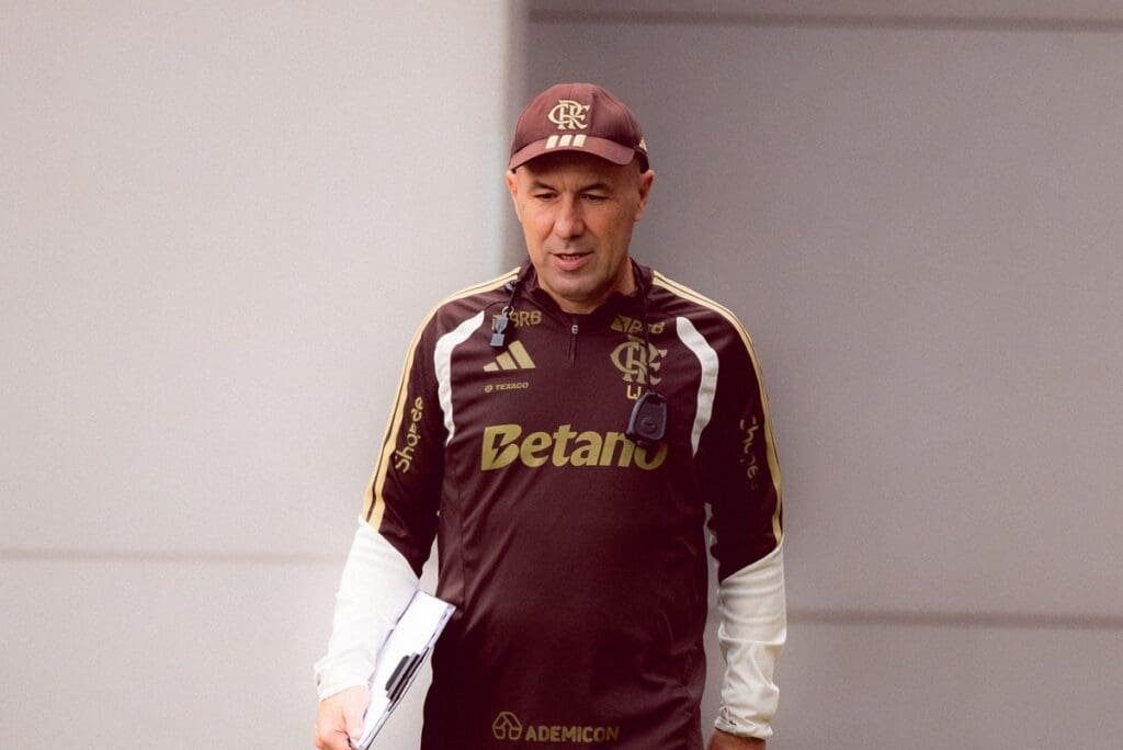 Leonardo Jardim olha para baixo e sorri enquanto caminha no Ninho do Urubu; treinador precisou fazer mudanças forçadas na escalação do Flamengo hoje