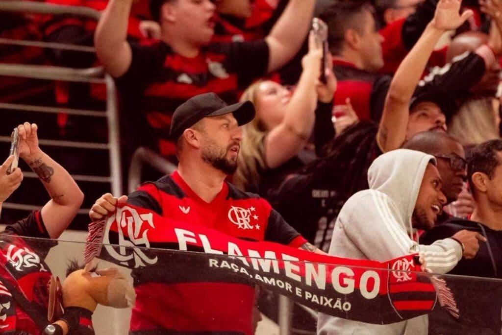 Flamengo lota estádios como visitante e gera renda superior a R$ 3 Mi no Brasileirão Torcedor do Flamengo na Arena da Baixada com faixa escrito "Flamengo Raça, Amor e Paixão"