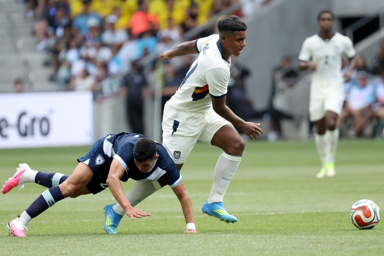 Jeremy Arevalo carrega a bola, enquanto Jonathan Franco cai no chão ao tentar acompanhar em Equador x Guatemala, que contou com Gonzalo Plata em campo