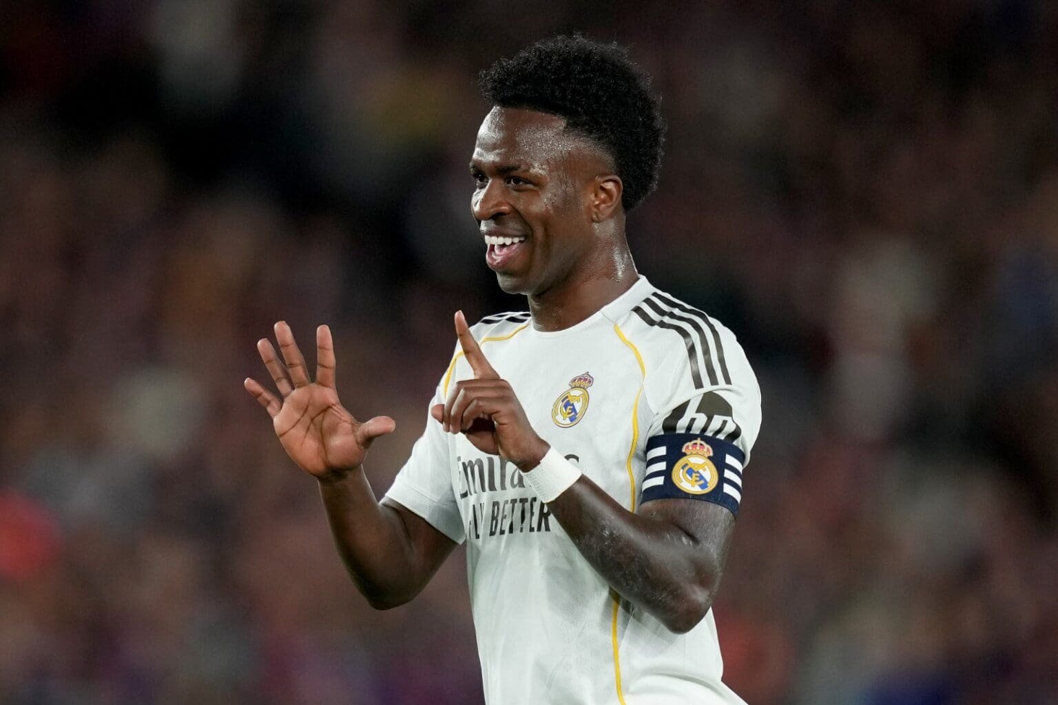 Vini Jr faz seis com as mãos e sorri durante jogo do Real Madrid