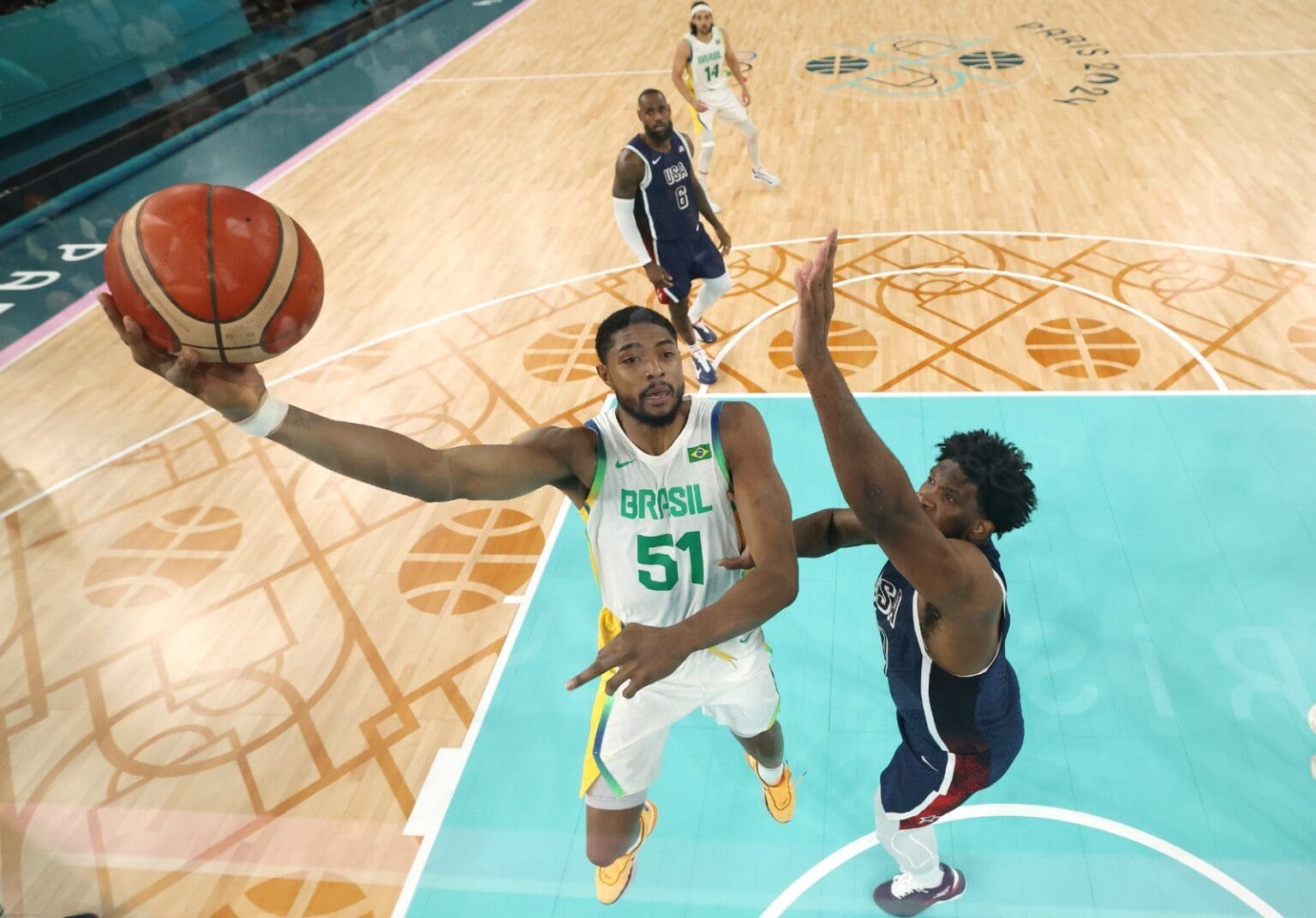 Bruno Caboclo faz a bandeija enquanto é marcado por Joel Embiid e observado por Lebon James durante Brasil x EUA das Olimpíadas de Paris 2024