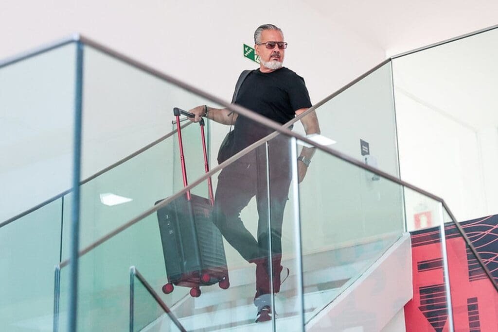 José Boto desce escadas do Ninho do Urubu segurando uma mala