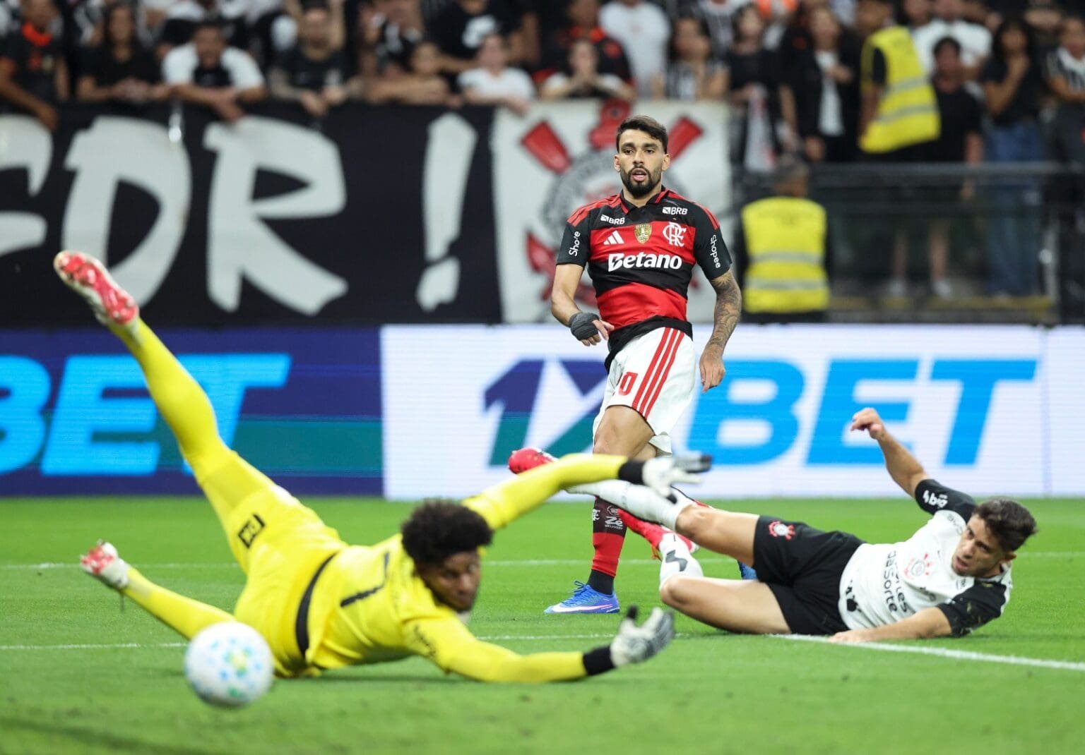 Onde assistir Flamengo x Corinthians ao vivo hoje: horário, canais e guia do jogo Lucas Paquetá obersva a bola indo em direção ao gol, assim como Hugo Souza e Gabriel Paulista, do Corinthians; saiba onde assistir Flamengo x Corinthians