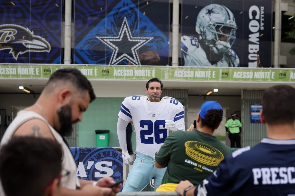 Torcedor tira foto em totem do Dallas Cowboys com recorte de rosto no entorno do Maracanã