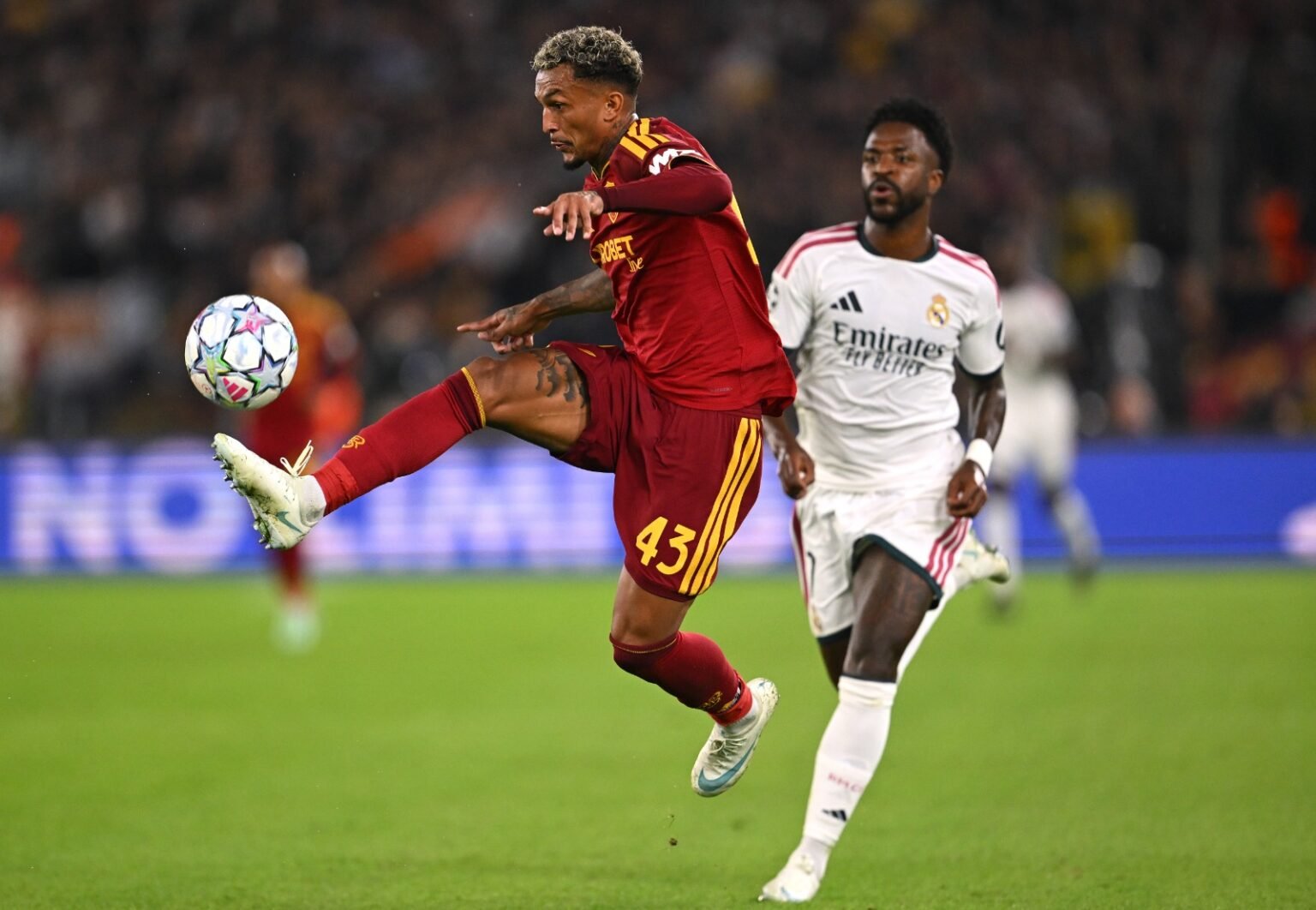 Wesley domina a bola durante Roma x Real Madrid, enquanto é perseguido por Vini Jr